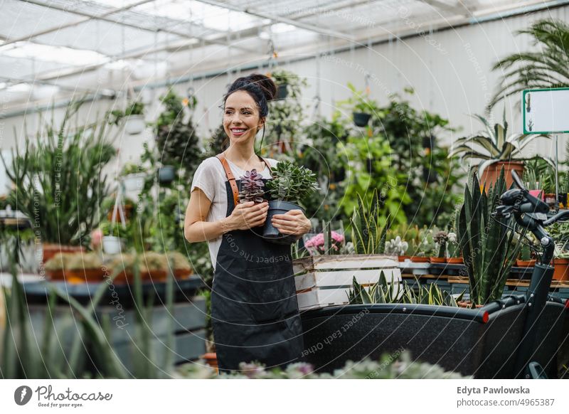 Frau arbeitet in einem Gartencenter Gärtnerei Lächeln Positivität Natur Gartenarbeit kultivieren Wachstum Hobby Frische Pflanze wachsend Flora grün Blumen