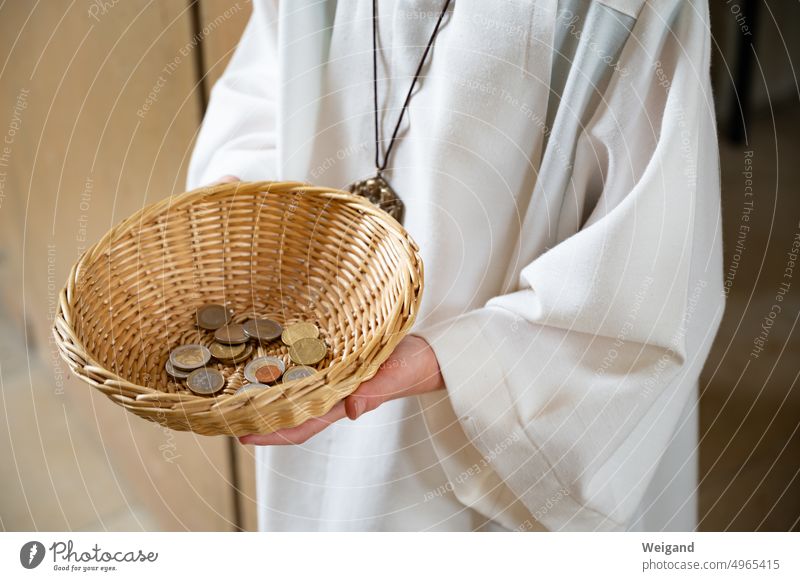 Person in weißer Kutte hält beigen Rattankorb mit Kleingeld in den Händen Ministrant Kirche Kollekte Kirchensteuer Spende Gabe Kirchenleben Korb halten