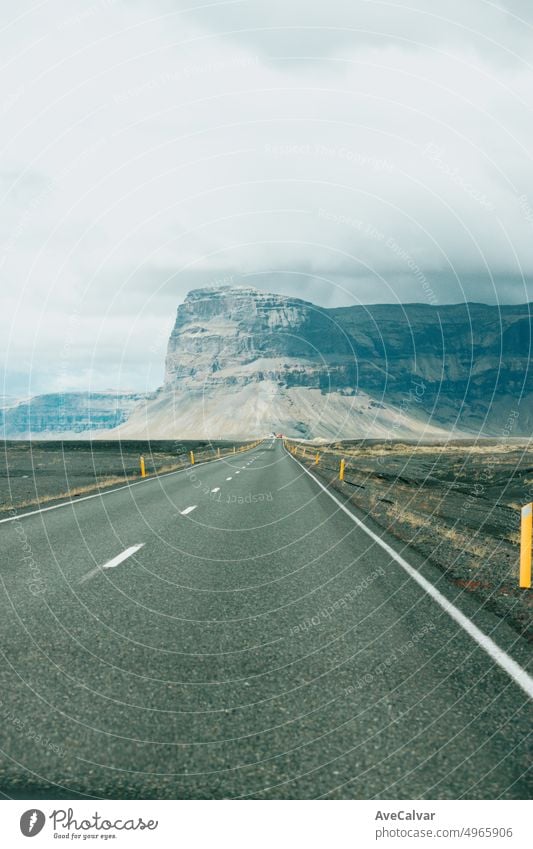Massiver Berg mit Canyon auf Island, Ende einer unendlichen Straße. Blick von der Straße während einer Reise durch isländische wilde Gebiete. Boho Backpacking Reisen Stil, Natur Hintergrund Konzept. Bunt
