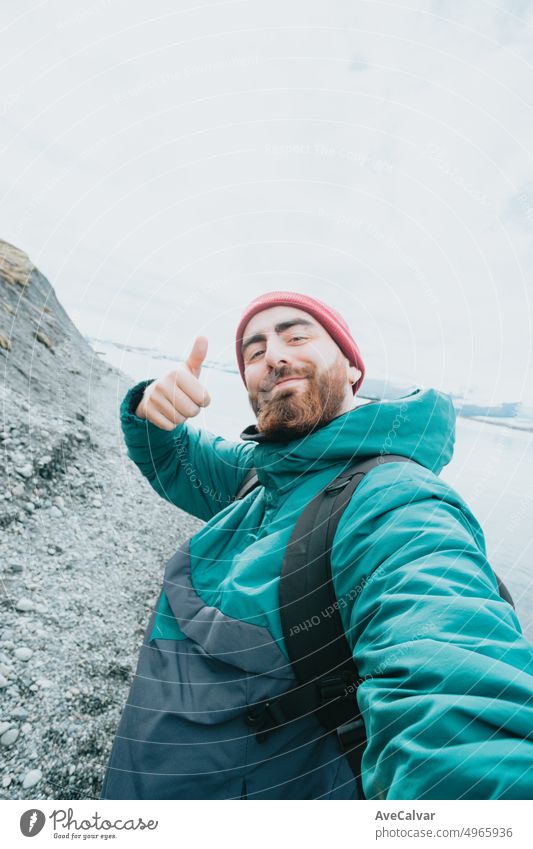 Solo männlicher Reisender auf Island glücklich bout Road Trip neue Erfahrungen. Lebendige Freiheit und erkunden Rucksacktourismus. Bearded Hipster gut aussehend Kerl tun die alle guten Zeichen für die Kamera ein Selfie beim Wandern zu nehmen.