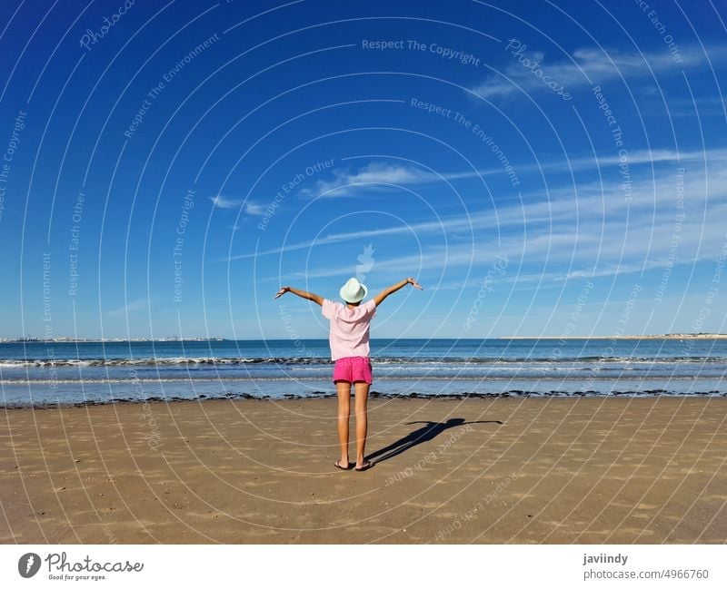 Mädchen mit Hut öffnet die Arme vor dem Meer, an einem Sandstrand. Strand Kind Sommer MEER Rücken Baby sich[Akk] entspannen Wasser Person Natur Urlaub tropisch