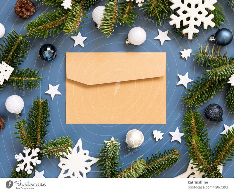 Bastelpapier Umschlag auf einem blauen Hintergrund in der Nähe von weißen Weihnachtsschmuck und Tannenzweige Weihnachten Kuvert Attrappe Stubenschmuck