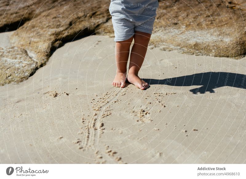 Crop Barfuß Kind auf Sandstrand Strand Uferlinie Sommer Kindheit nass Fuß Natur Meeresufer Küste wenig Harmonie stehen Urlaub sorgenfrei Sonnenlicht idyllisch