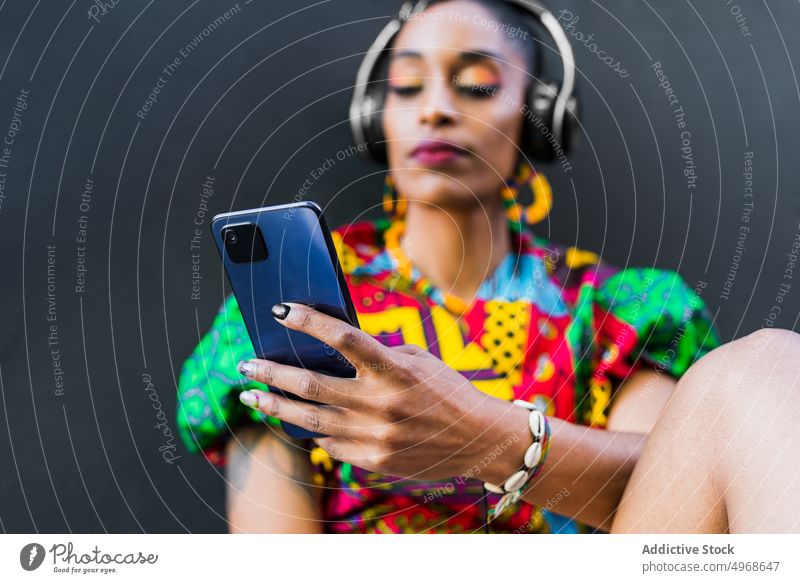 Ethnische Frau benutzt Smartphone auf einer Treppe benutzend Straße Schritt zuhören Musik soziale Netzwerke meloman Stil jung ethnisch Streetstyle urban