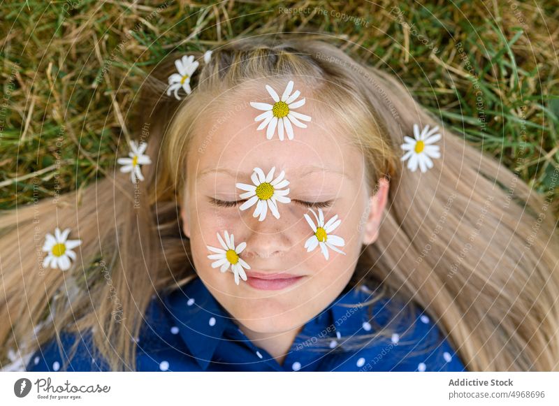 Mädchen mit Gänseblümchen im Gesicht Blume Lächeln Gras Feld Landschaft blond Glück Augen geschlossen Porträt Wochenende Blüte Blütezeit frisch Kind Wiese Natur
