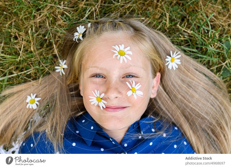 Mädchen mit Gänseblümchen im Gesicht Blume Lächeln Gras Feld Landschaft blond Glück Porträt Wochenende Blüte Blütezeit frisch Kind Wiese Natur Lügen Flora
