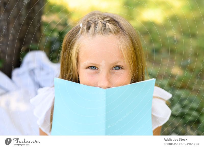 Mädchen mit Buch im Park Deckblatt Sommer Wochenende Etage tagsüber Freizeit blond graue Augen Saison Kindheit Natur Literatur lesen Notebook Notizblock Planer
