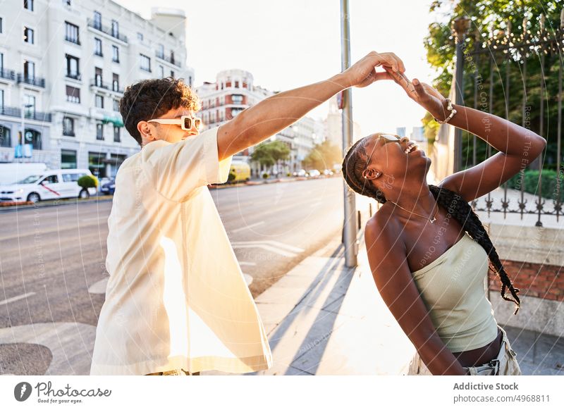 Glückliches buntes Paar tanzt auf der Straße Tanzen Zusammensein sich im Kreise drehen urban Lachen Stil Spaß haben Freundin jung vielfältig rassenübergreifend