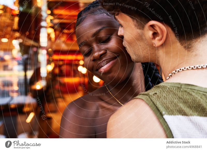 Mann küsst schwarze Freundin in der Nähe eines Restaurants Paar Kuss Termin & Datum Liebe Straße Glück romantisch Zuneigung Partnerschaft Lächeln Wange