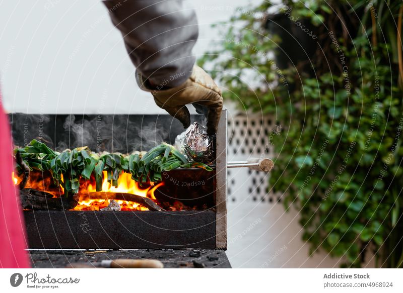 Unbekannte Person, die auf der Terrasse Kalbsbraten grillt Koch calcot Zwiebel Grillrost grillen traditionell authentisch Küche kulinarisch Lebensmittel