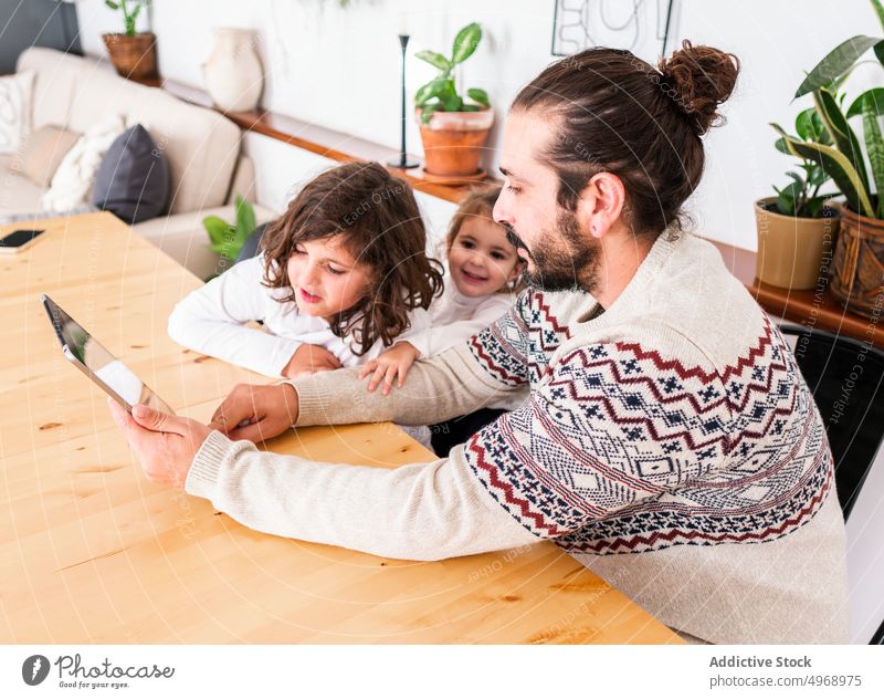 Mann und Kinder benutzen Tablette Vater Tisch Zusammensein Partnerschaft Appartement Gerät Glück männlich Mädchen hölzern benutzend sitzen Lächeln heimwärts