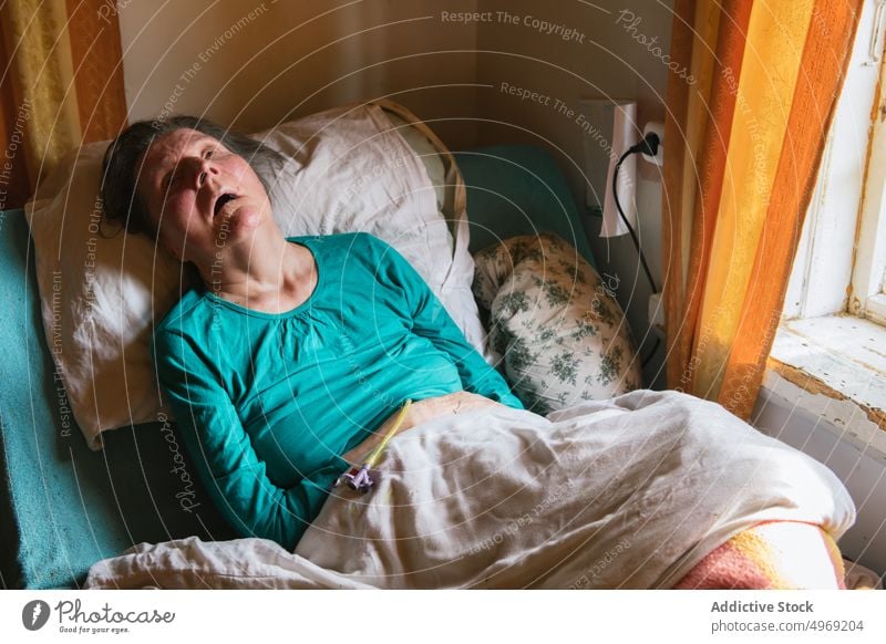 Gelähmte ältere Dame, die zu Hause auf dem Bett liegt Frau gelähmt heimwärts medizinisch Raum Behinderung Pflege geduldig Senior reif Rentnerin abstützen