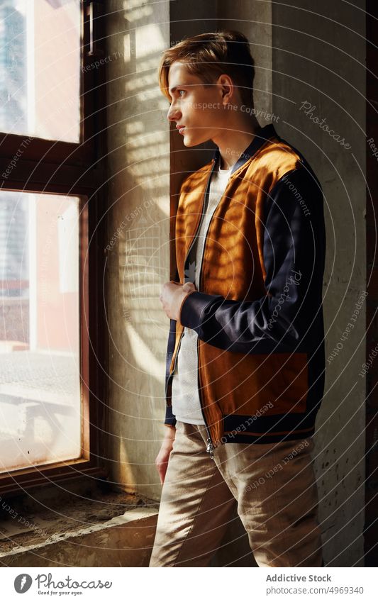 Junger Mann steht in der Nähe von Fenstern posierend Model gutaussehend entspannt urban trendy stylisch Sommer jung männlich Typ attraktiv Selbstvertrauen ernst