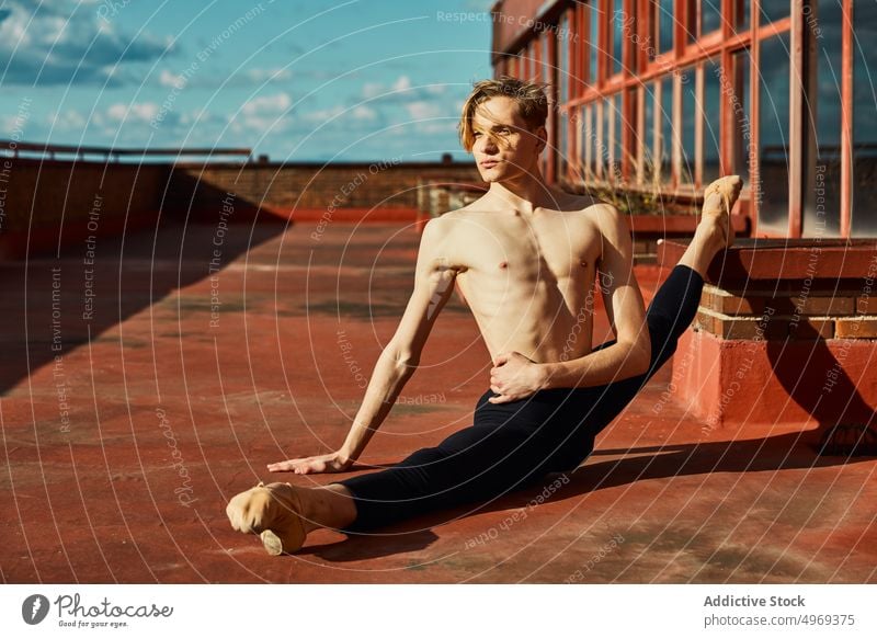 Junge schlanke Darstellerin macht Spagat auf dem Dach Ballett-Tänzerin verrichtend talentiert zierlich beweglich leer strecken jung Mann männlich Athlet