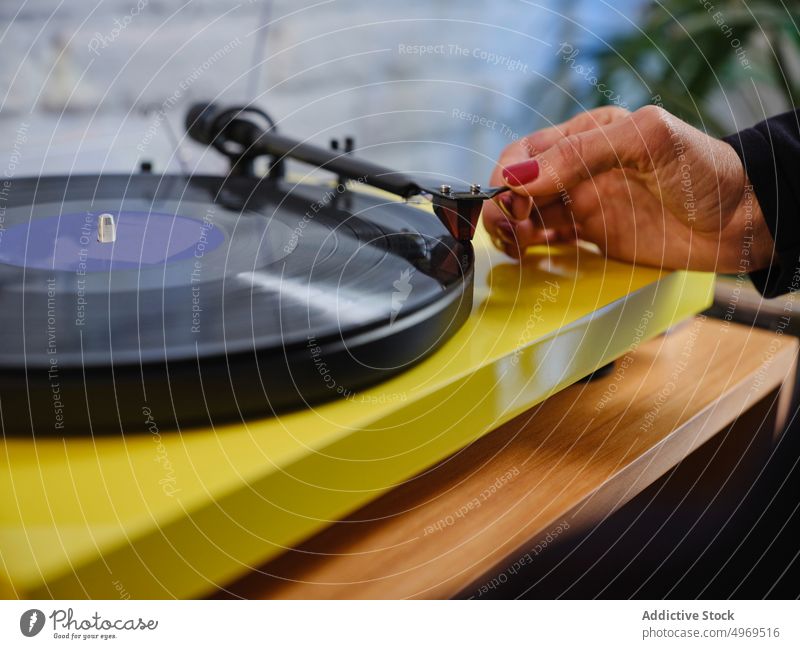 Frau legt Schallplatte in Plattenspieler Aufzeichnen Spieler Vinyl Musik Scheibe Nostalgie zuhören elegant Hobby genießen Melodie Jacke altehrwürdig Audio Klang