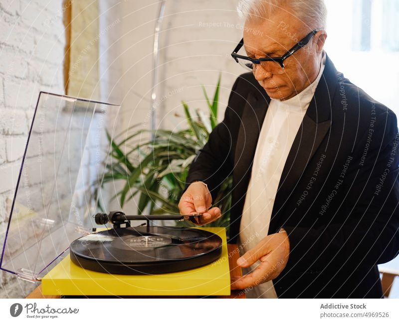 Älterer Mann legt Schallplatte in Plattenspieler Aufzeichnen Spieler Vinyl Musik gealtert Scheibe Nostalgie Senior zuhören retro elegant männlich Hobby genießen