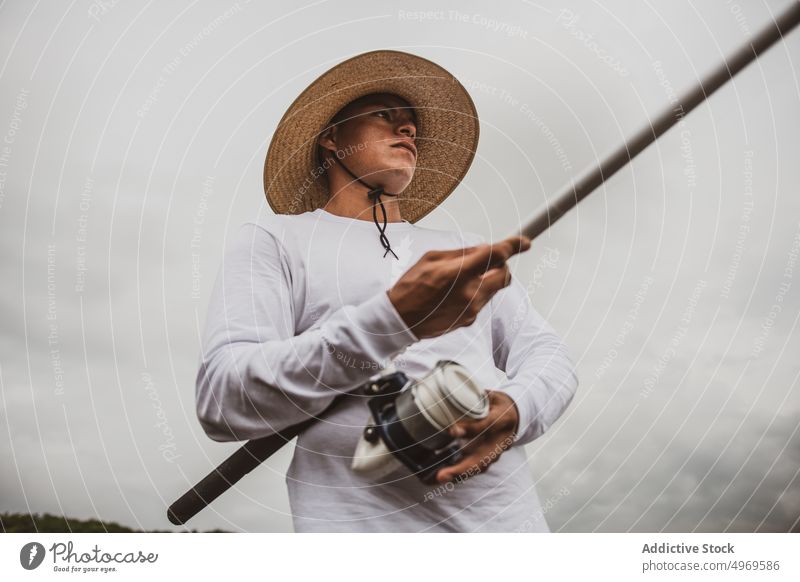 Mann beim Fischen am Meeresufer Fischer Stab Küste Ufer Hobby Gerät MEER fangen Freizeit männlich Seeküste Hut Angler Fähigkeit Wasser Lifestyle ruhen Typ