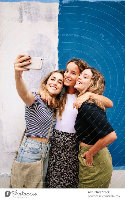 Gruppe von angenehmen Frauen, die ein Selfie mit ihrem Smartphone machen, in der Nähe der Brücke Selfie nehmen Bild umarmend Fotoapparat benutzend Straße