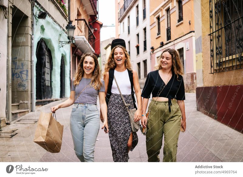 Mädchen, die sich umarmen und auf der Straße gehen Frauen sprechend Sitzung Freundschaft laufen Bonden Freunde Menschengruppe heiter lässig Lächeln Zusammensein