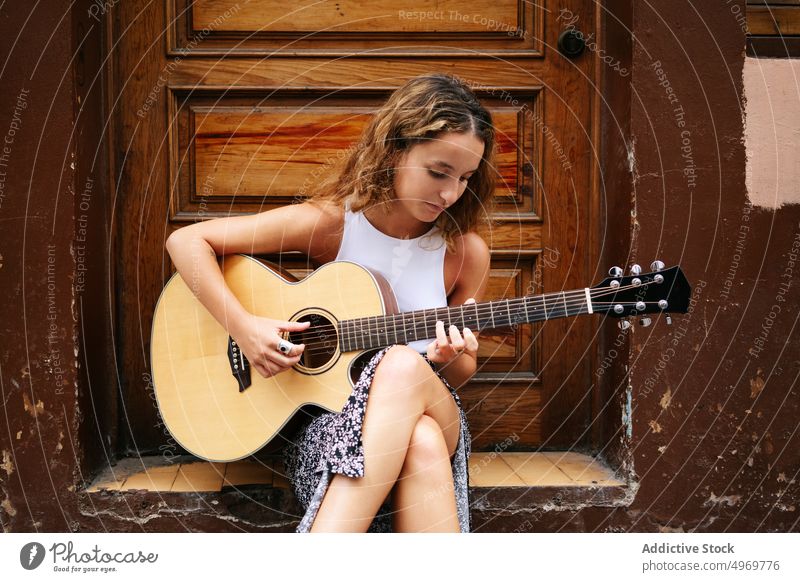 Frau spielt Gitarre auf der Straße Sitzen Gebäude Musik Architektur Instrument Musical geometrisch urban Urlaub Mode Haus Feiertag lässig Sommer kreativ