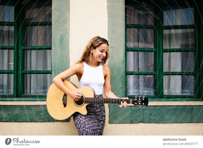 Frau spielt Gitarre auf der Straße Sitzen Gebäude Musik Architektur Instrument Musical geometrisch urban Urlaub Mode Haus Feiertag lässig Sommer kreativ