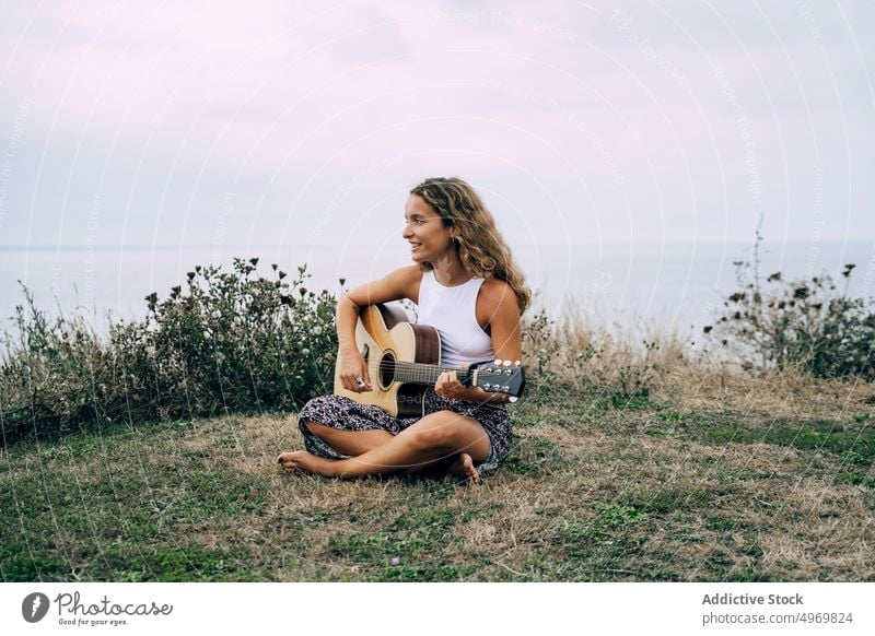 Frau spielt Gitarre in einem Feld mit trockener Vegetation Musik Spielen romantisch jung spielen Instrument heiter Musical Spaß Urlaub Mode Feiertag lässig