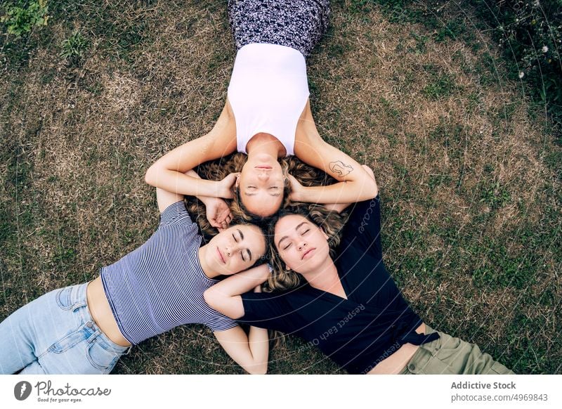 Entspannte Freundin im Gras liegend mit Köpfen im Kreis und lachen Frauen Park Freunde Lügen Rasen Freundschaft Zusammensein heiter attraktiv Spaß