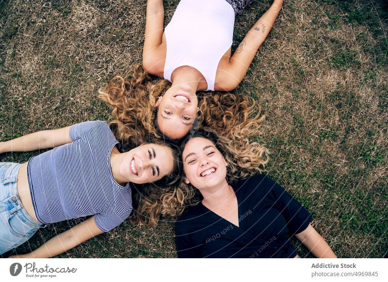 Entspannte Freundin im Gras liegend mit Köpfen im Kreis und lachen Frauen Park Freunde Lügen Rasen Glück Freundschaft Lächeln Zusammensein heiter attraktiv Spaß
