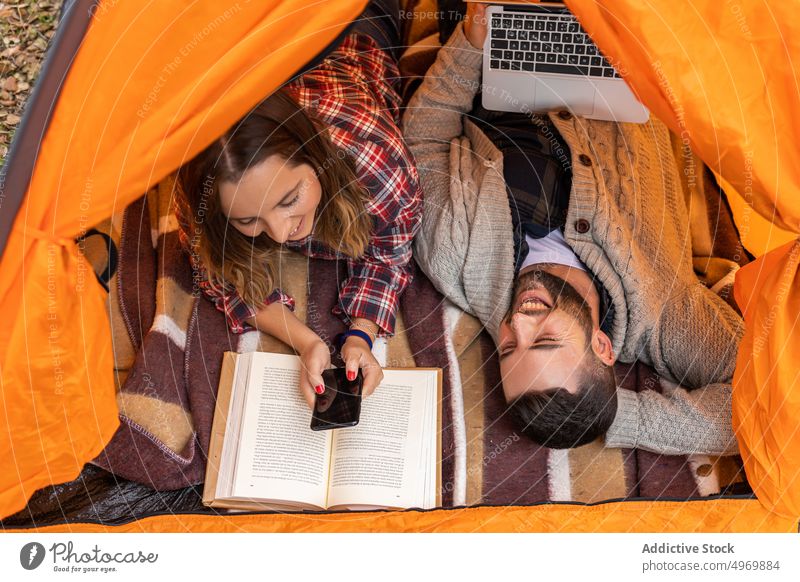 Camping-Paar im Zelt mit Gadgets Urlaub Feiertage jung orange Laptop Freund aktiv Zusammensein Smartphone Partnerschaft Computer Liebe Apparatur Browsen