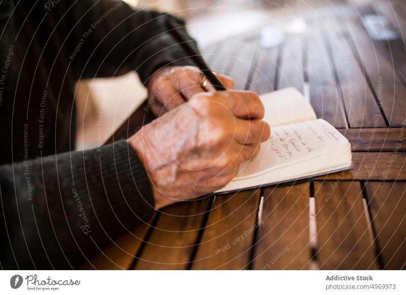älterer Mann schreibt in sein Notizbuch Lifestyle klug Ausdruck Konstruktion männlich Business Notebook grau heimwärts Person im Innenbereich Schriftstück