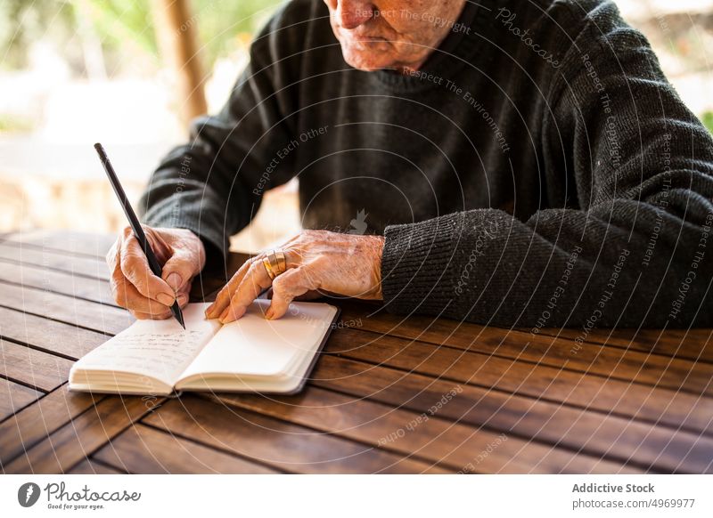 älterer Mann schreibt in sein Notizbuch Lifestyle klug Ausdruck Konstruktion männlich Business Notebook grau heimwärts Person im Innenbereich Schriftstück
