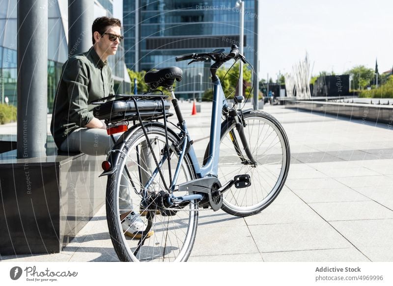 Trendy Mann sitzt mit Fahrrad in der Innenstadt Großstadt Stadtzentrum urban Straße geparkt Stil Fahrzeug Megapolis männlich modern Zentrum Verkehr trendy