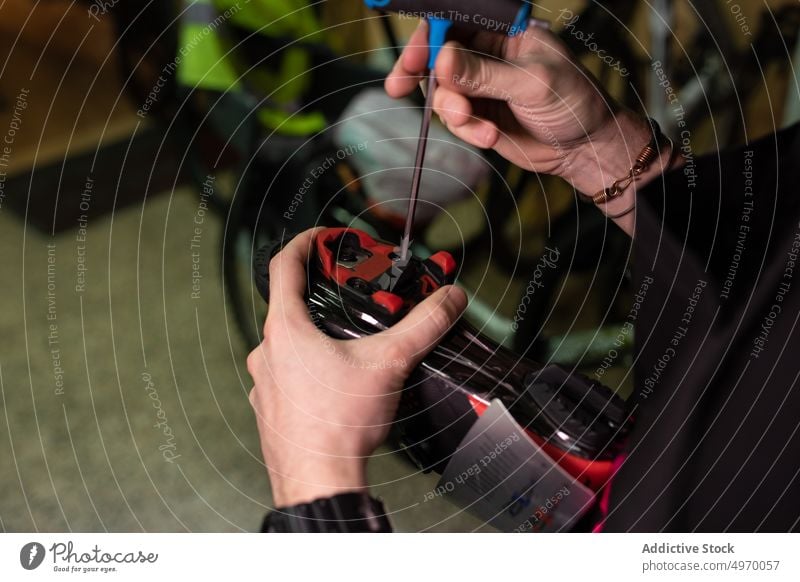 Crop-Techniker repariert Fahrradschuh Mechaniker fixieren Werkstatt Schuh Fahrradfahren schrauben Schraubendreher Arbeit Dienst Garage Reparatur Werkzeug modern