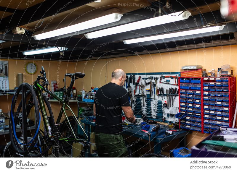 Kahlköpfiger Mechaniker in der Fahrradwerkstatt Werkstatt Hobelbank Mann Reparatur Anpassung Arbeit kahl Erwachsener Dienst Job professionell konzentriert