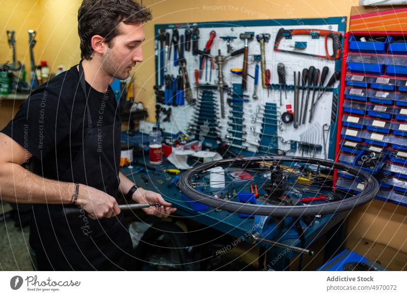 Männlicher Mechaniker pumpt Fahrradreifen auf Werkstatt Pumpe Rad Air Hobelbank Mann Reparatur Anpassung Arbeit Werkzeug Dienst Job professionell konzentriert