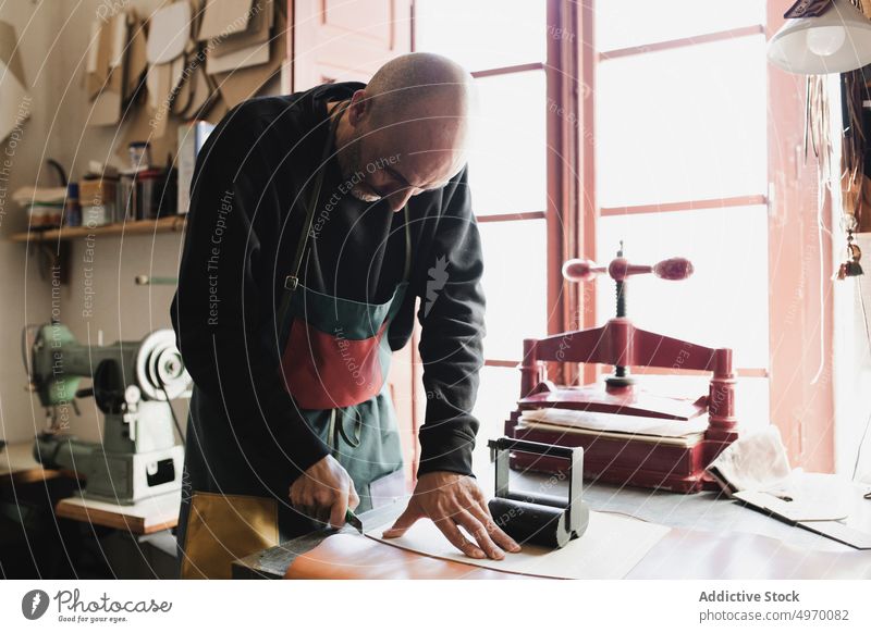 Mann schneidet Textil im Atelier Schneider Werkstatt Leder Schneiden Nähmaschine dickey Presse Arbeitsplatz Mode Bekleidung Damenschneiderin Design Handwerk
