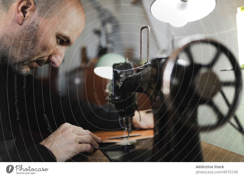 Mann beim Nähen von Textilien im Atelier Schneider Werkstatt Näherei Nähmaschine Hand Arbeitsplatz Mode Bekleidung Damenschneiderin Design Handwerk Gewebe