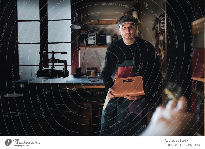 Mann hält Ledertasche Kunsthandwerker Werkstatt dunkel männlich Hut Arbeit manuell Tasche traditionell Herstellung Material erschaffend Prozess Vorbereitung