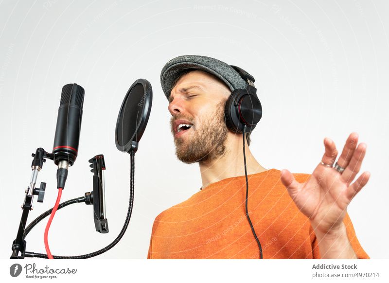 Talentierter Mann mit Smartphone nimmt Song im Studio auf Aufnahme Atelier Gesang singen Mikrofon Audio Musik Stimme Funktelefon Handy Bildschirm Mobile Gerät
