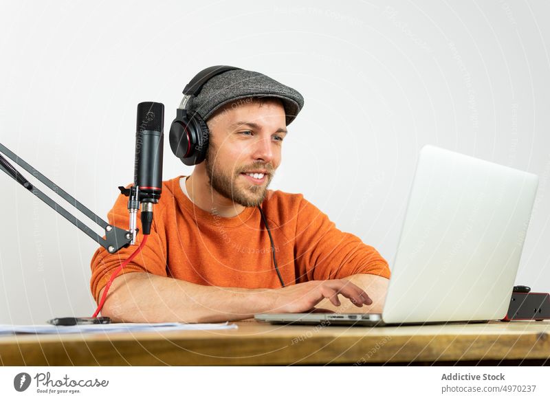 Konzentrierter Mann, der am Laptop surft und Dokumente liest, während er im Studio aufnimmt Kopfhörer zuhören Audio Browsen Mikrofon Aufnahme Atelier