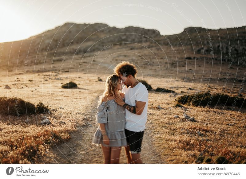 Fröhliches erwachsenes Paar, das sich bei Sonnenuntergang im Hochland umarmt Umarmen Liebe sinnlich Glück Hügel Hipster romantisch Partnerschaft Romantik