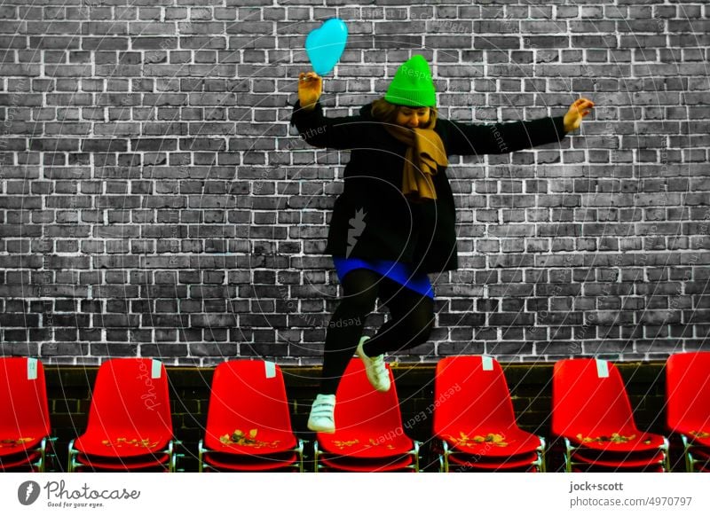 springe dich frei von der Stuhlreihe Frau Mensch Sprung springen Freiheit Bewegung Lebensfreude Stühle Reihe Backsteinwand Design Luftballon Winterjacke Mütze