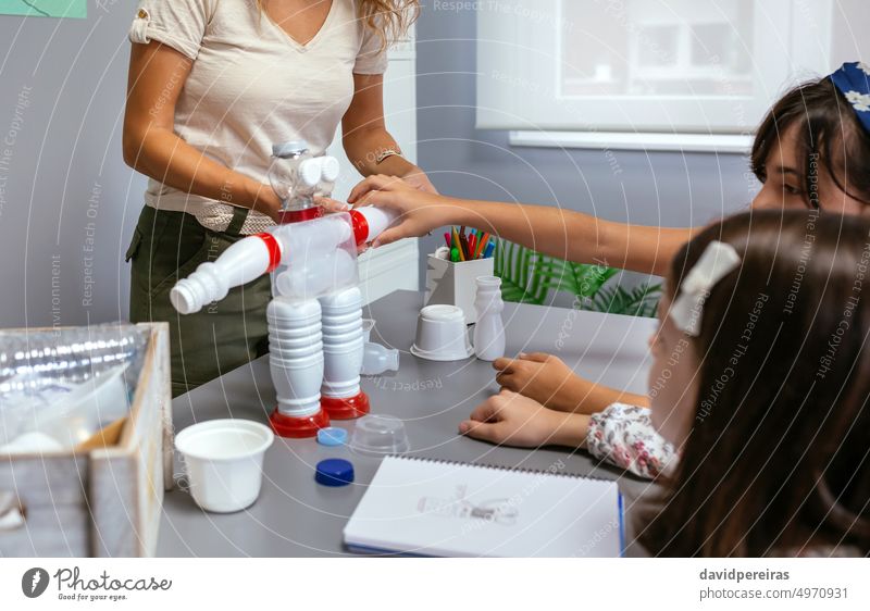 Ein Schüler setzt ein Teil in einen recycelten Spielzeugroboter aus Plastikverpackungen ein Kind Kinder Roboter robotisch wiederverwertet wiederverwenden
