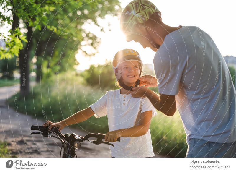Aufnahme eines Vaters, der den Helm seines Sohnes zurechtrückt Tag Gesunder Lebensstil aktiver Lebensstil im Freien Spaß Freude Fahrrad Fahrradfahren Radfahren
