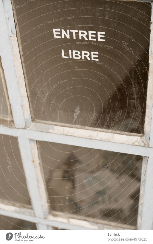Eintritt frei entree libre steht auf einer Glasstür geschrieben, viel ungelesene Post ist auf dem Boden im inneren zu sehen Glastür Schrift Briefe schmutzig