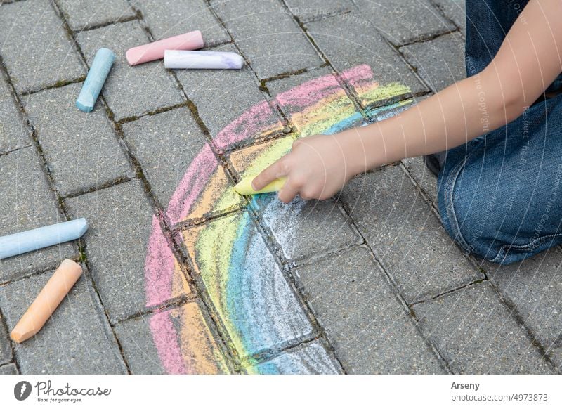 Ein Kind malt mit farbiger Kreide einen Regenbogen auf die Straße. Selektiver Fokus. Kind. Ein Kind spielt draußen Person im Freien Kunst zeichnen Aktivität