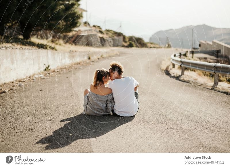 Glückliches erwachsenes Paar genießt einander auf der Straße im Hochland sitzend Liebe Freundin Hipster romantisch Angebot sinnlich Weg Partnerschaft Asphalt