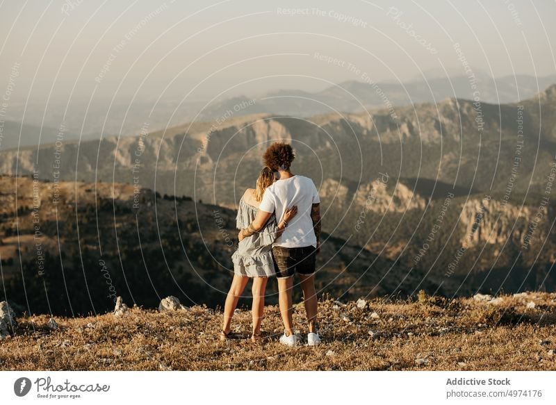Glückliches Paar genießt die Aussicht auf das Hochland, während es auf einem Hügel steht und sich umarmt Berge u. Gebirge Umarmung reisen romantisch Park