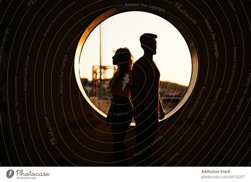 Paar steht Rücken an Rücken vor dem Fenster bei Sonnenuntergang Partnerschaft Freude Architektur Zuneigung Golfloch rund Freund Freundin Bonden Termin & Datum