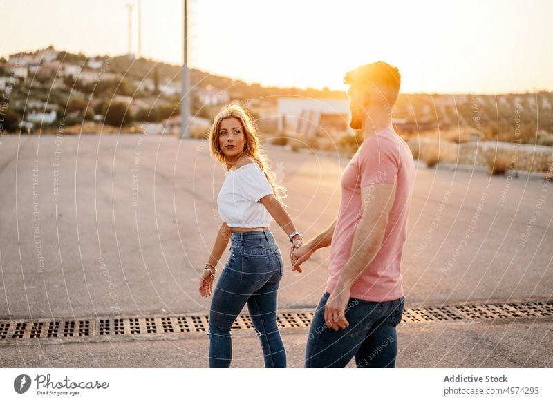 Junges Paar spaziert händchenhaltend auf der Straße in der Abenddämmerung Liebe Glück Umarmung Partnerschaft Stadt Freundin heiter Sonnenuntergang aufgeregt